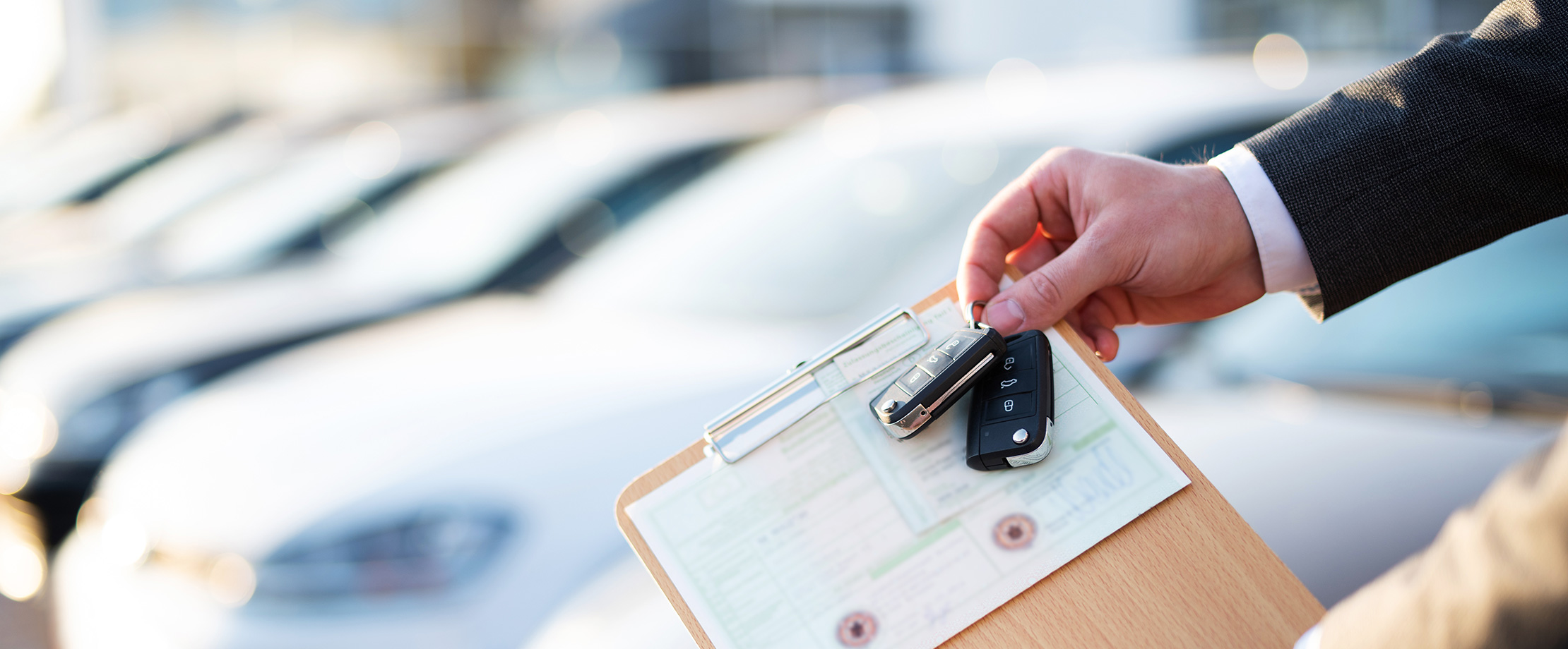 Jemand hält von rechts einen unterzeichneten Leasing-Vertrag und Autoschlüssel in die Kamera. 