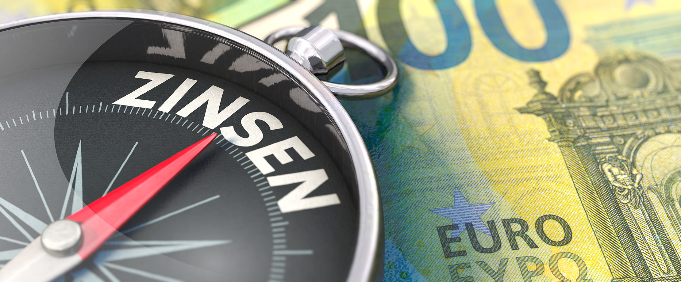 Auf einem 100-Euro-Schein liegt ein Kompass, dessen Kompassnadel auf das Wort „Zinsen“ zeigt.